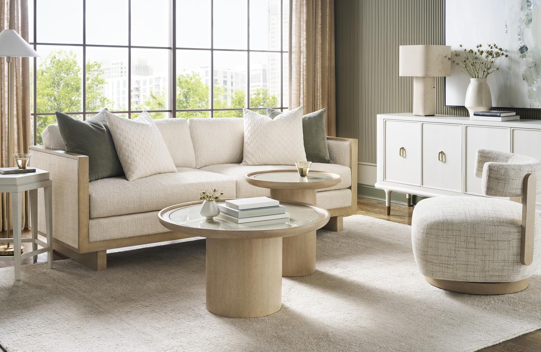 Light living room with a linen sofa, round cocktail tables and white sideboard